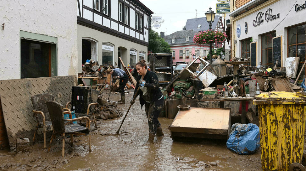 مواطنون يزيلون الأنقاض من شارع في باد نوينار أرفايلر بغرب ألمانيا بعد الفيضانات المدمرة