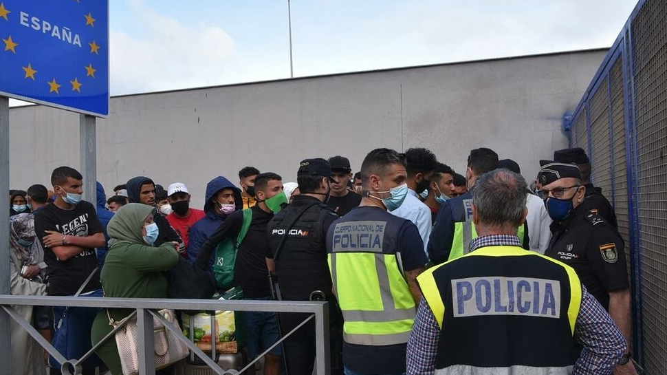 رجال شرطة إسبان يقفون إلى جانب المهاجرين الذين ينتظرون عبور الحدود إلى المغرب سبتة في 20 ماي 2021