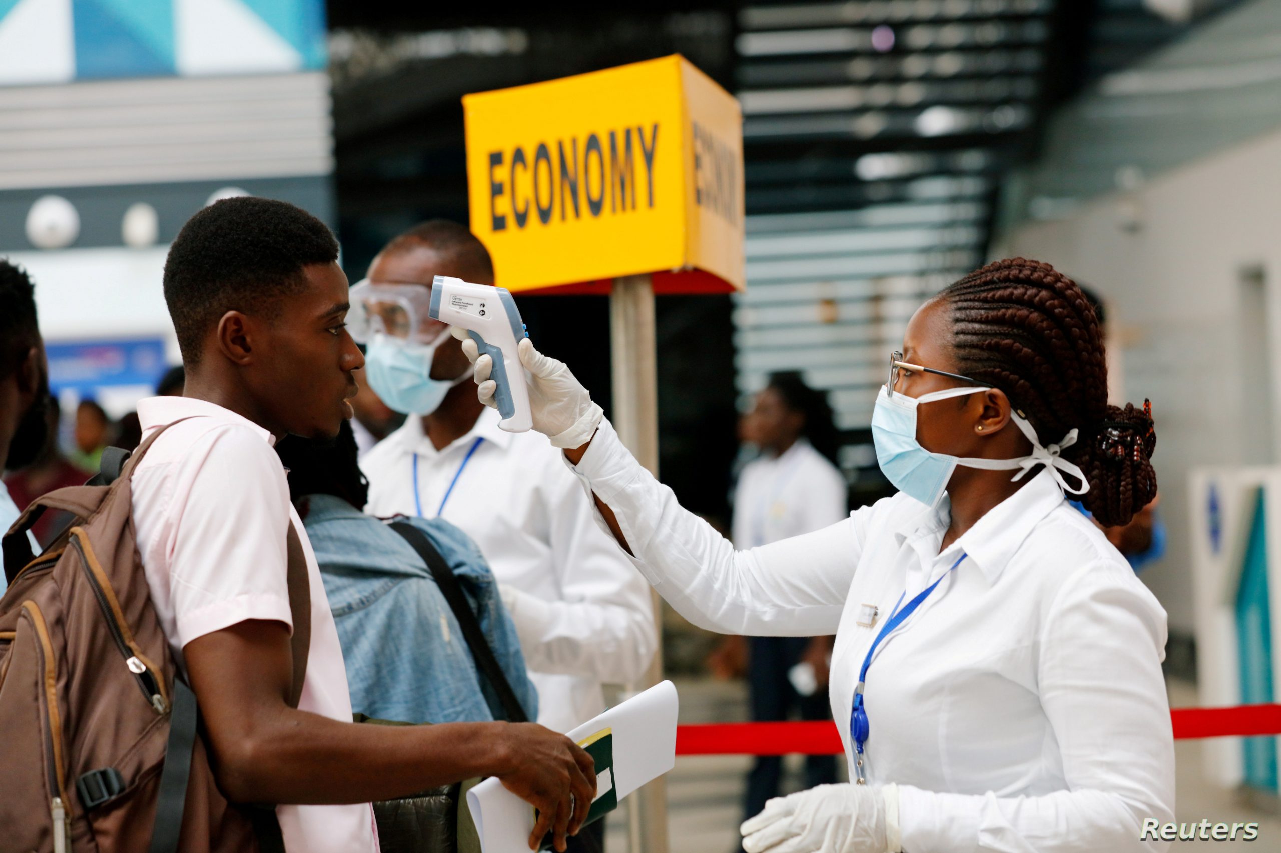 FILE PHOTO: A health worker checks the temperature of a traveller as part of the coronavirus screening procedure at the Kotoka International Airport in Accra,