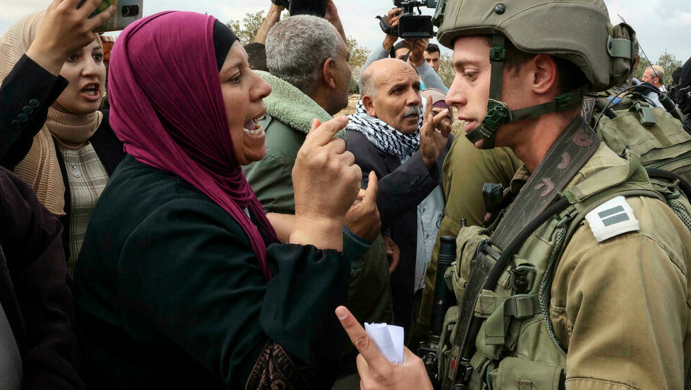 جندي إسرائيلي يجادل امرأة فلسطينية من قرية سوسية خلال مواجهات مع مستوطنين من مستوطنة تحمل نفس الاسم