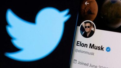 حساب إيلون ماسك على تويتر على هاتف ذكي أمام شعار شبكة التواصل الاجتماعي