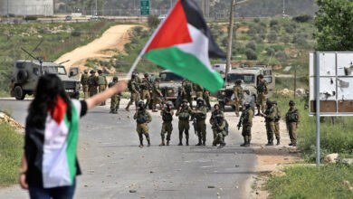 A Palestinian protester waves her national flag in front of Israeli security forces during a protest marking the Palestinian Land Day