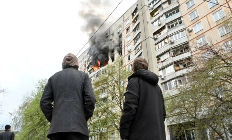 مارة يشاهدون الحريق الناجم عن ضربة على شقة في شمال خاركيف في شرق أوكرانيا
