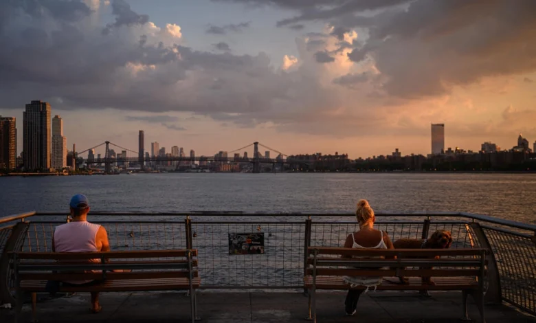 صورة التُقطت في الثاني من غشت 2022 تُظهر شخصين يجلسان أمام نهر ايست ريفر في بروكلين في نيويورك