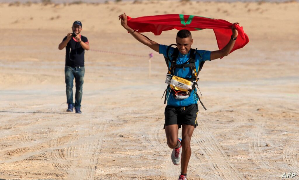 محمد المرابطي لحظة وصوله إلى خط النهاية حاملا العلم المغربي محتفيا بالفوز بالمرحلة الثانية