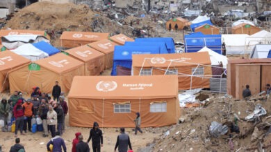 فلسطينيون يحتمون في خيام أقيمت وسط مبانٍ تضررت بشدة يحملون عبوات بلاستيكية لملئها بالمياه في جباليا في شمال قطاع غزة في 6 فبراير 2025.